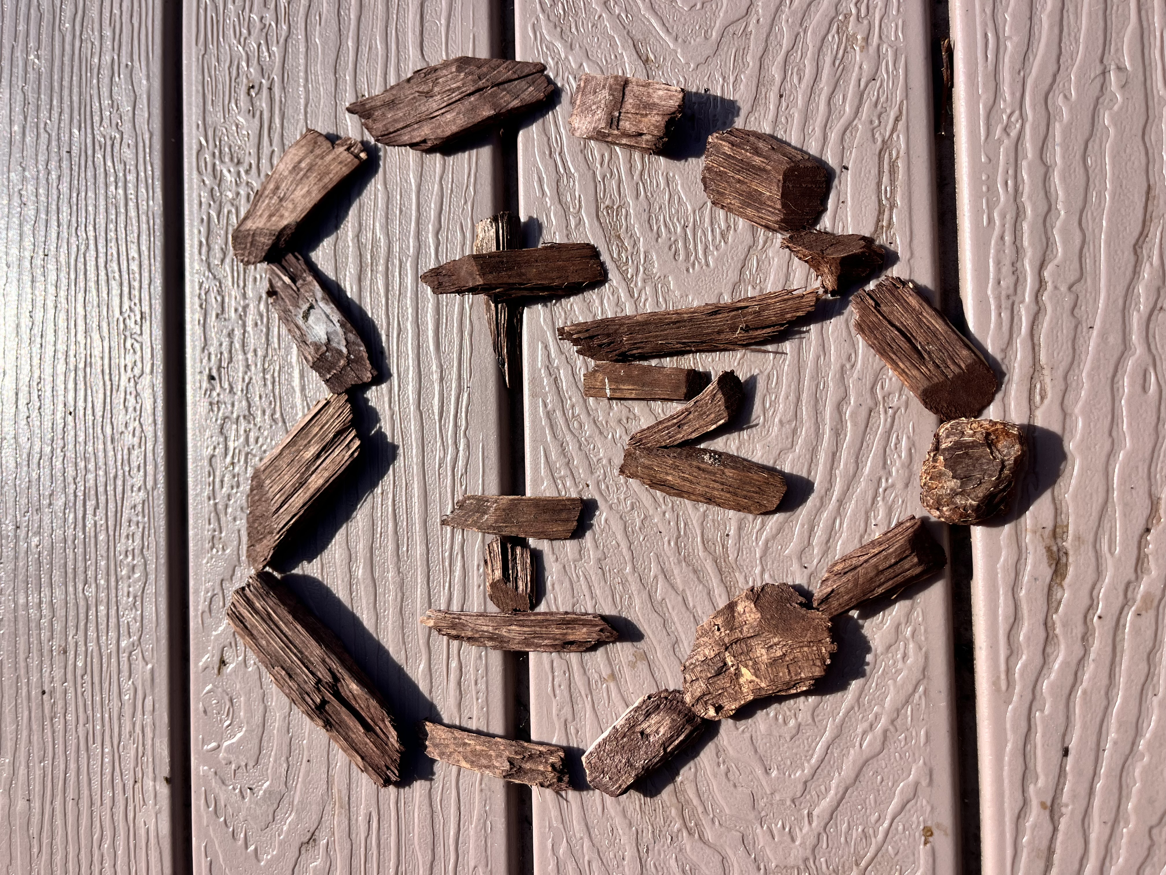 Driftwood arranged into an M & H and hearts on a wooden deck.